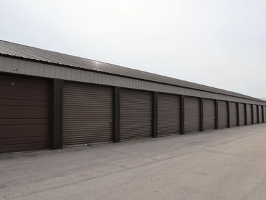 A row of closed brown storage unit doors under a metal roof.