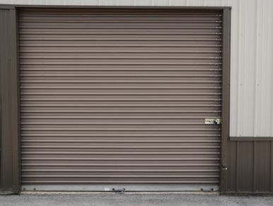 Closed brown metal roll-up garage door on a building.