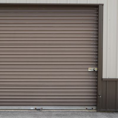 Closed brown metal roll-up garage door on a building.