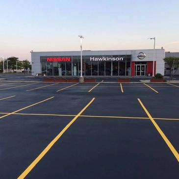 Empty parking lot in front of a Nissan dealership named Hawkinson.