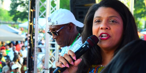 Woman speaking into microphone at outdoor event.