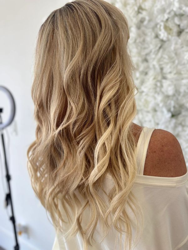 Long, wavy blonde hair cascading down the back with soft curls.