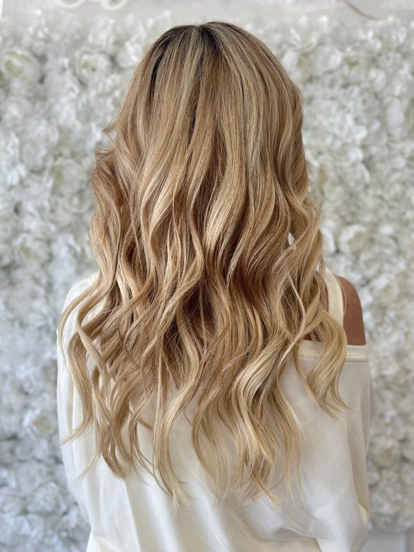 Long, wavy blonde hair styled beautifully against a floral backdrop.
