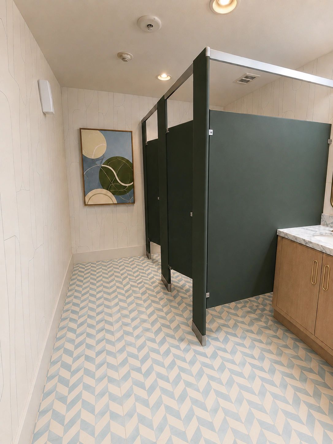 Modern restroom with geometric tile flooring and dark green stalls.