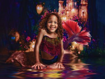 Little girl as a mermaid reflected in the water in front of an enchanted castle