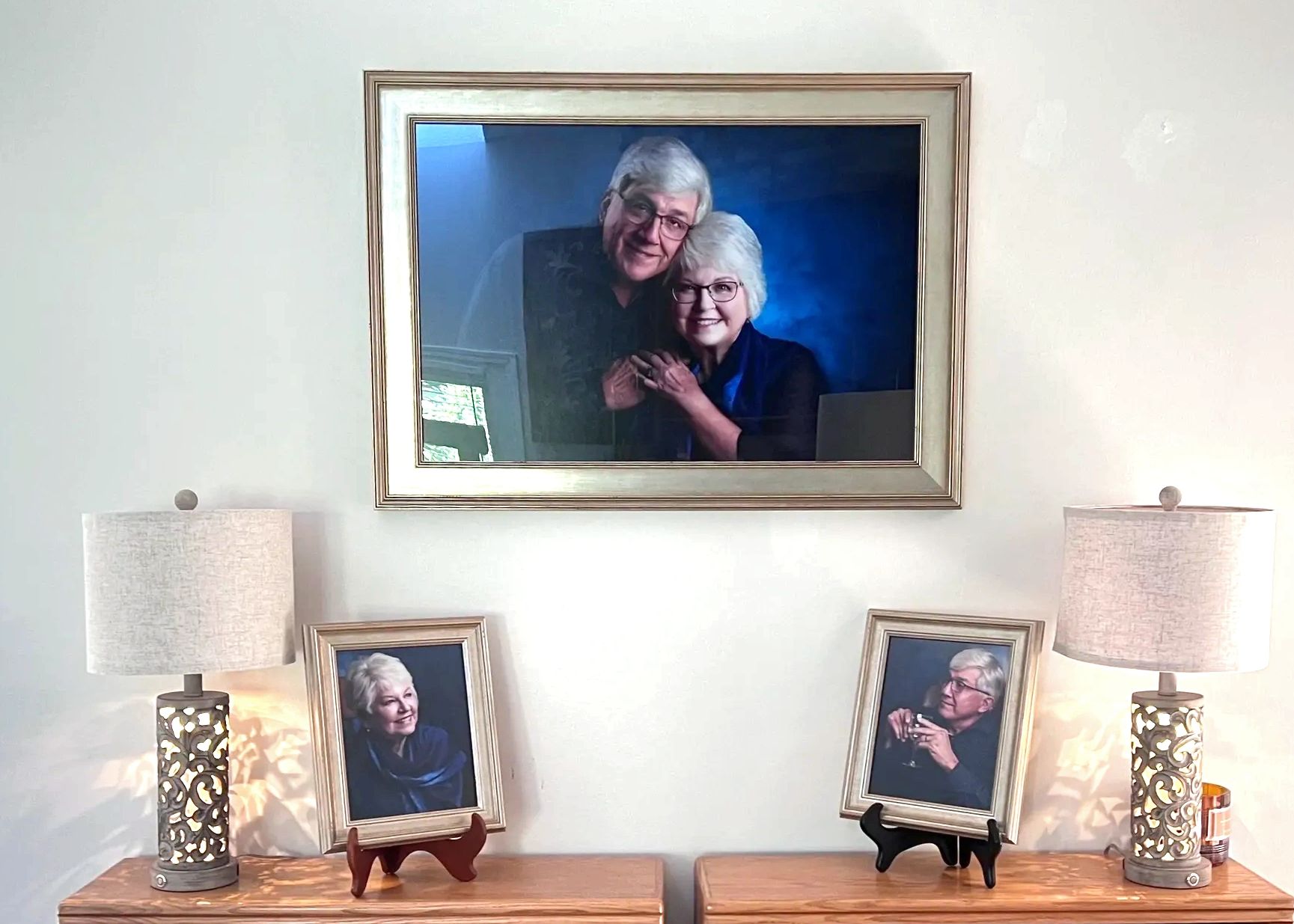 Beautiful anniversary portrait of silver-haired couple in gold frames displayed in their home.