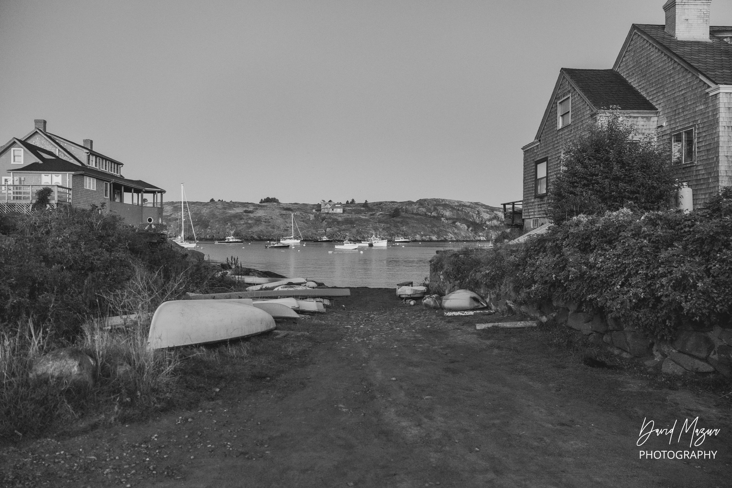 Seaside scene with boats and houses in black and white.