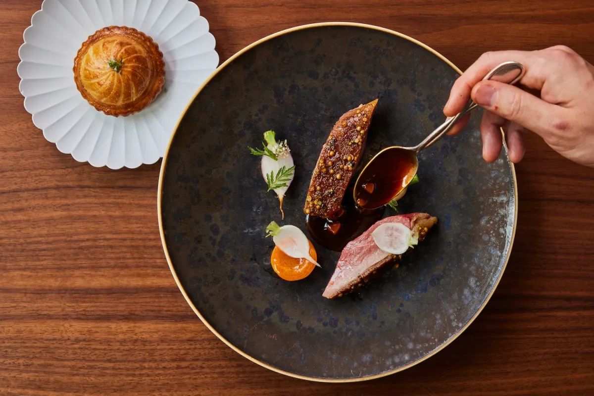 Elegant plated gourmet dish with sauce drizzle and a pastry on the side.