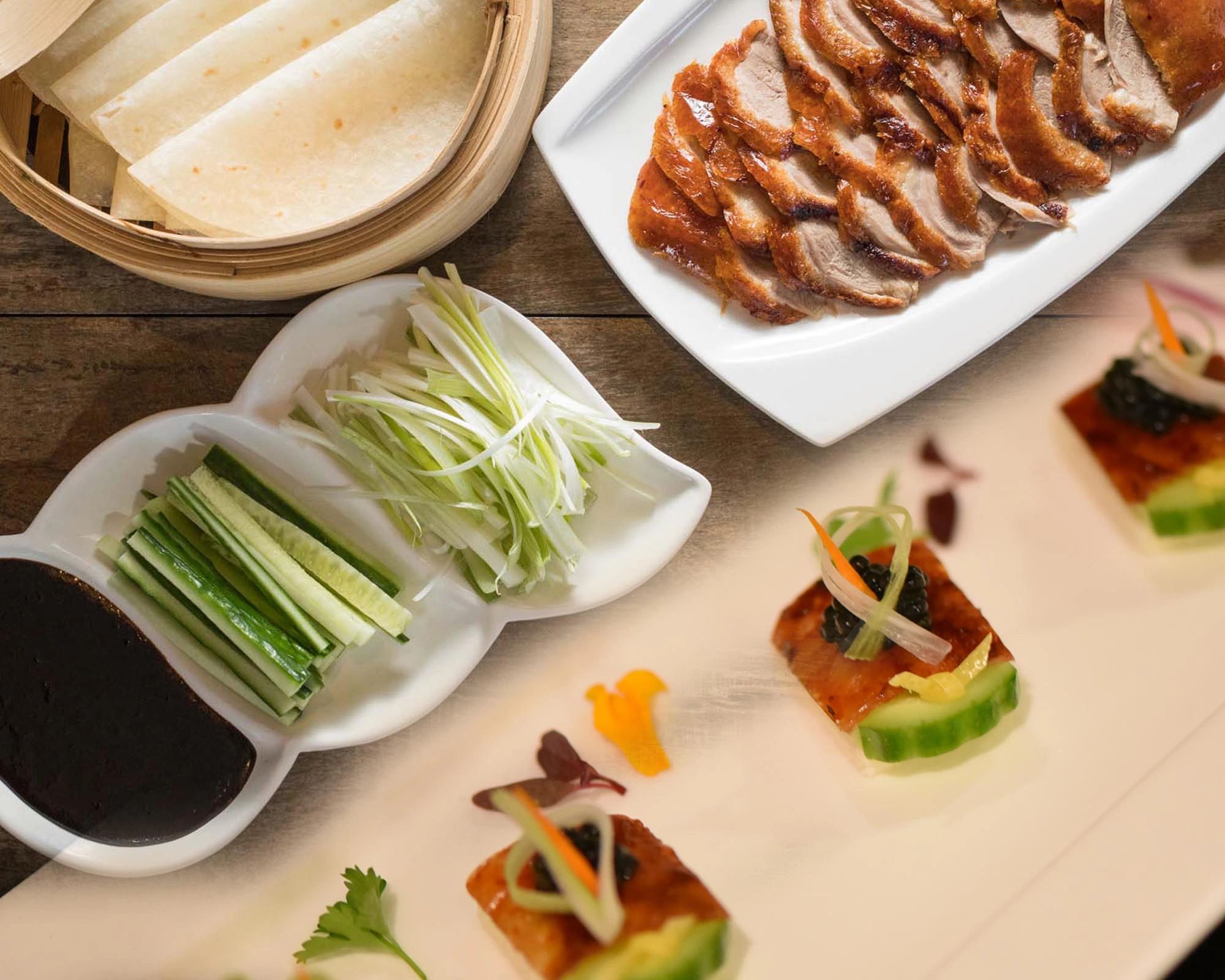 Elegant Peking duck with pancakes, cucumber, scallions, and sauce.