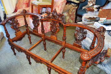 Intricately carved antique wooden sofa frame without cushions.