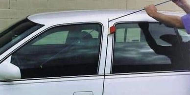 A Person Opening The Door Of A White Color Car With A Tool