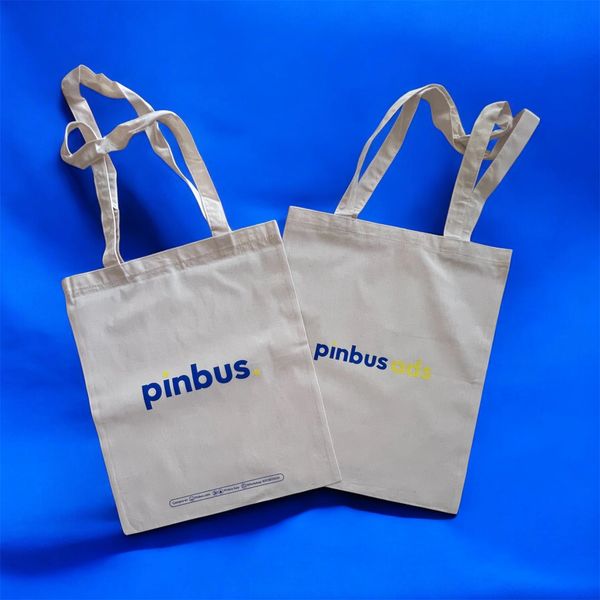 Two beige tote bags with 'pinbus' logo on a blue background.