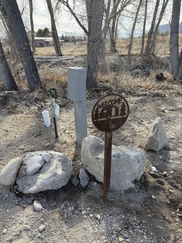 Metal sign in a rocky outdoor area saying welcome.