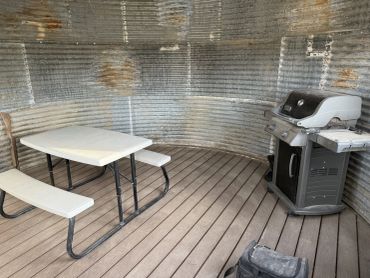 Picnic table and grill inside a round metal shelter.