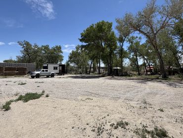 A dirt lot with trees and a white truck.