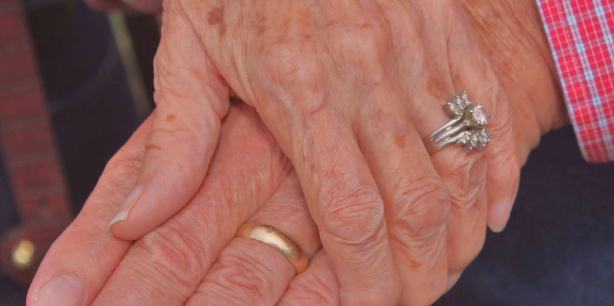 Two elderly people holding hands