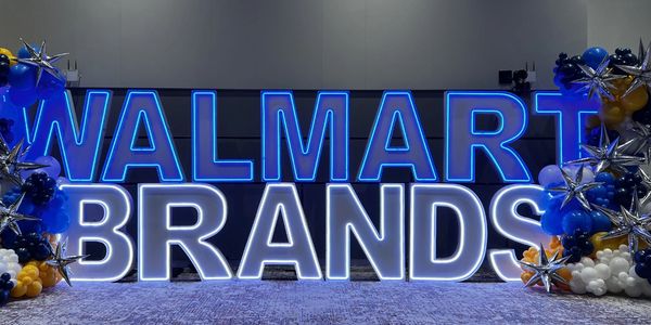 Illuminated sign displaying 'Walmart Brands' with decorative balloon arrangements.
