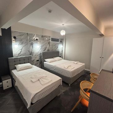 Modern twin bed hotel room with elegant lighting and minimalist decor.