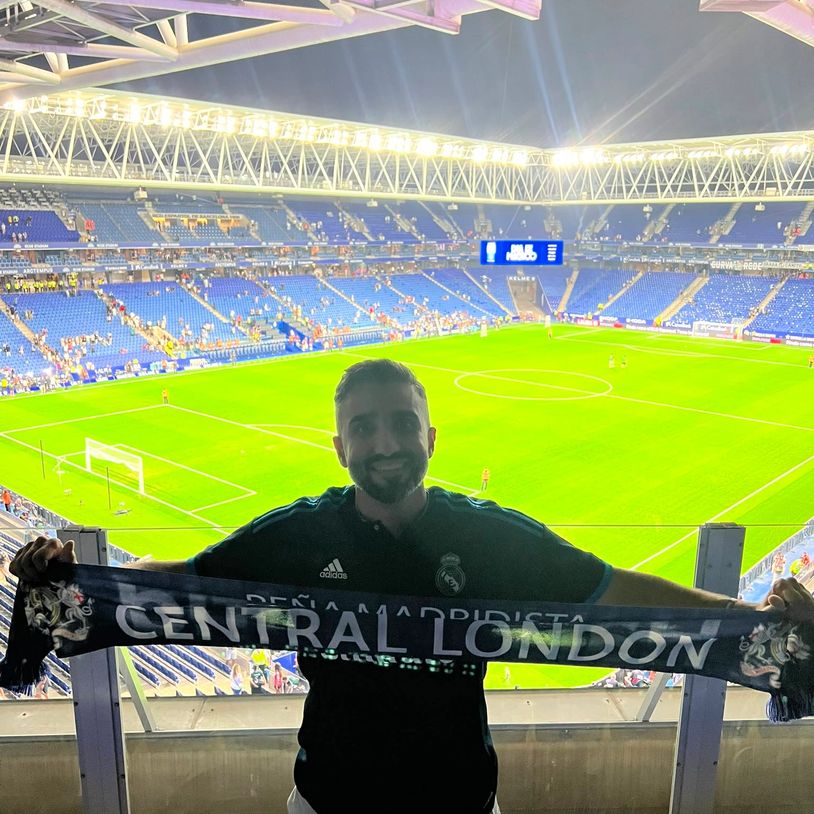 Fan holding a Central London scarf in a soccer stadium.