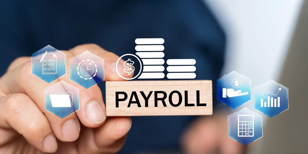 Hand holding a block labelled PAYROLL with financial icons, representing payroll management services