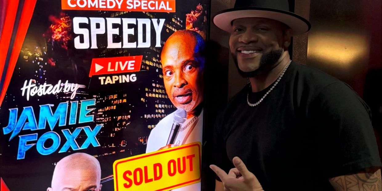Man posing next to a comedy special poster.