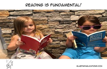 Two young children engrossed in reading books against a stone wall.