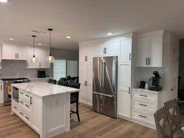 Modern kitchen with white cabinets, marble island, and stainless steel appliances.