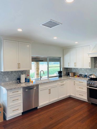 Kitchen with white cabinets, granite countertops, porcelain sink and stainless steel appliances