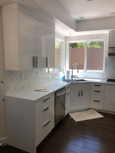 Kitchen with white cabinets, quartz countertop, stainless steel sink and appliances, and two windows