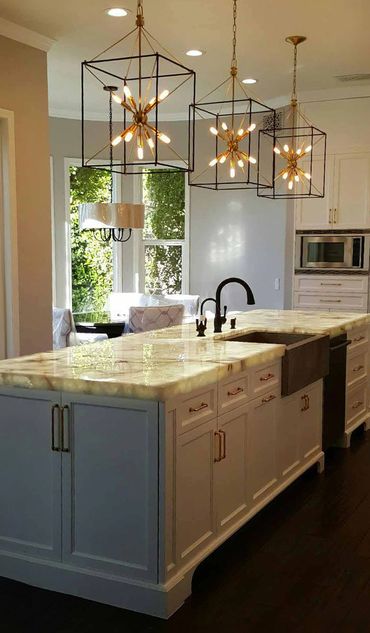 Kitchen with a center island, granite top, cooper sink, black faucets, & three large pendant lights