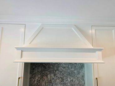 White wooden kitchen hood with decorative molding and marble backsplash.