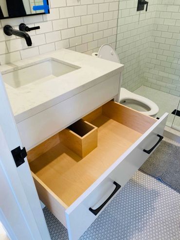 Small white bathroom cabinet with a white quartz countertop and sink with black faucets and hardware