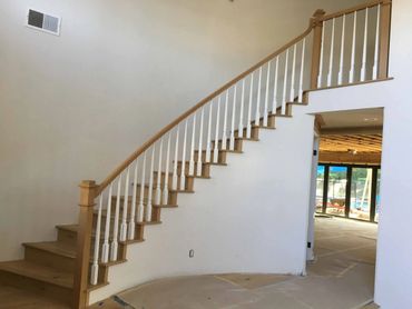 Wooden staircase with white spindles in a modern home under construction.