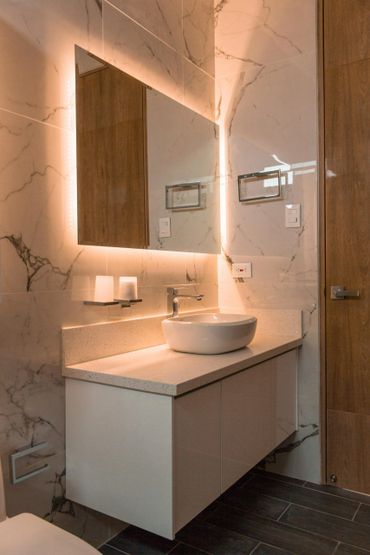 Freestanding bathroom cabinet with an above countertop oval sink and a large backlit mirror