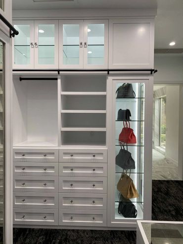 Custom white cabinet with glass doors above, open shelving, lower drawers, and clothing rack