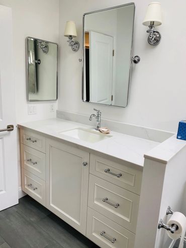 White cabinet with a white counter and and sink, with a mirror above the sink