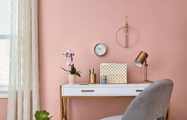 Stylish workspace with a white desk, gold accents, and a pink wall.