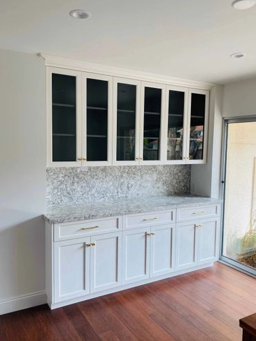 Custom white cabinets with stone countertop and backsplash and glass upper cabinets 
