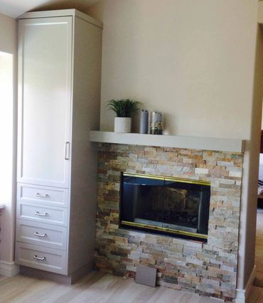 Small light color custom cabinet with an adjacent stone fireplace