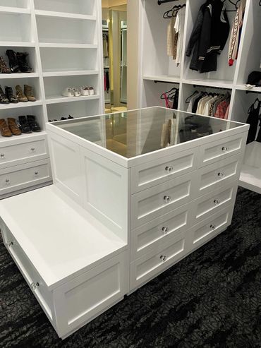 Custom white closet with open and closed cabinets and a built-in center isle cabinet