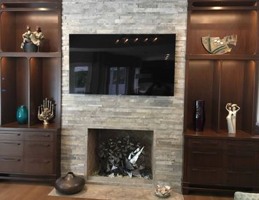 Stone fireplace with a TV above and two built-in wood cabinets on both sides of the fireplace