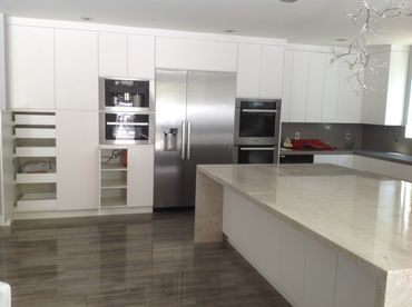 Modern kitchen with white cabinets and marble island.