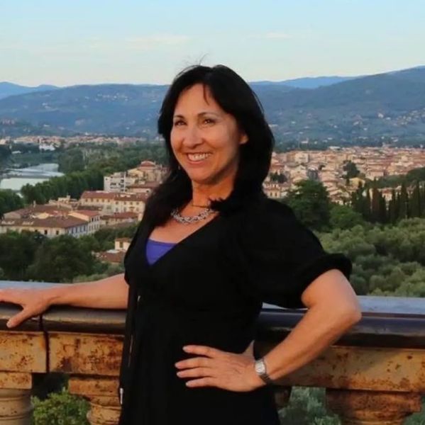 Woman posing with a scenic city and mountain view in the background.