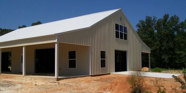 50x60 Enclosed Pole Barn with two lean-tos. White exterior panels, windows and garage door in the gable end of the building.