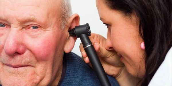 A qualified Audiologist looking in a patient's ear to check the ear canal for ear wax or infections 