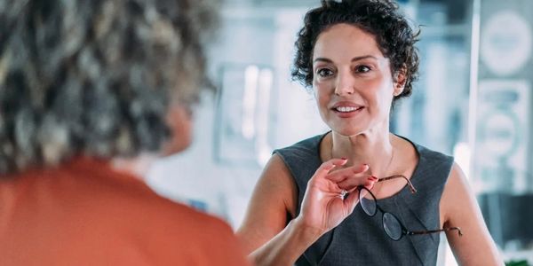 Two women engaged in a friendly conversation in a modern office setting.