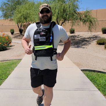 Man jogging outdoors wearing a weighted vest labeled 'Beast Mode'.