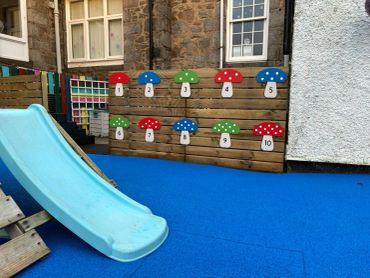 Playground slide with colorful numbered mushroom targets on a wall.