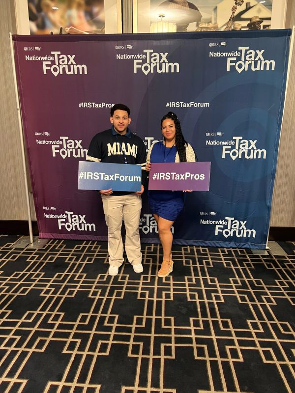 Two people pose at the Nationwide Tax Forum event holding signs.