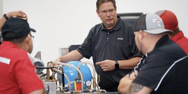 Instructor explaining technical equipment to a group of men.